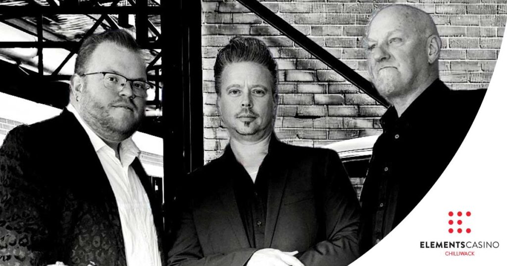 Three men in suits pose for a black-and-white photo in front of a brick wall, embodying sophistication and style. The Elements Casino Chilliwack logo is displayed in the bottom right corner, adding a touch of modern flair to the timeless scene.