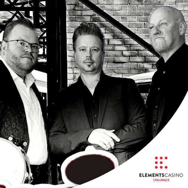 Three men dressed in dark suits stand together in front of a brick wall, exuding a sense of sophistication. The logo for Elements Casino Chilliwack appears in the bottom right corner, subtly highlighting the venue. The photo is black and white.