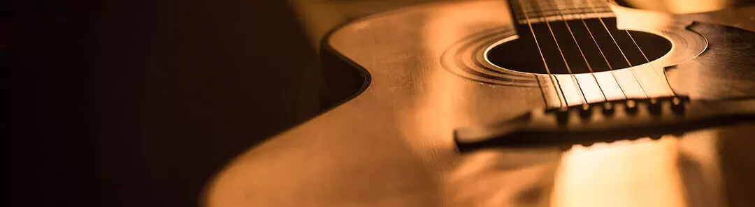 Close-up of the body and strings of an acoustic guitar.